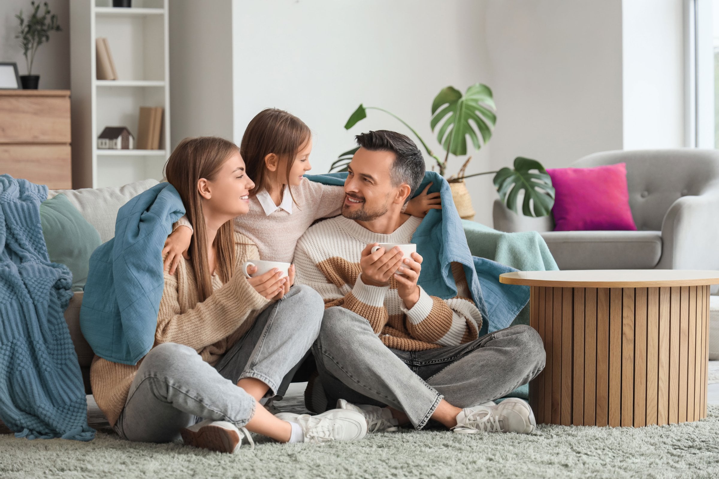 Famiglia felice e protetta in un soggiorno accogliente: l'importanza di una polizza assicurazione casa completa.